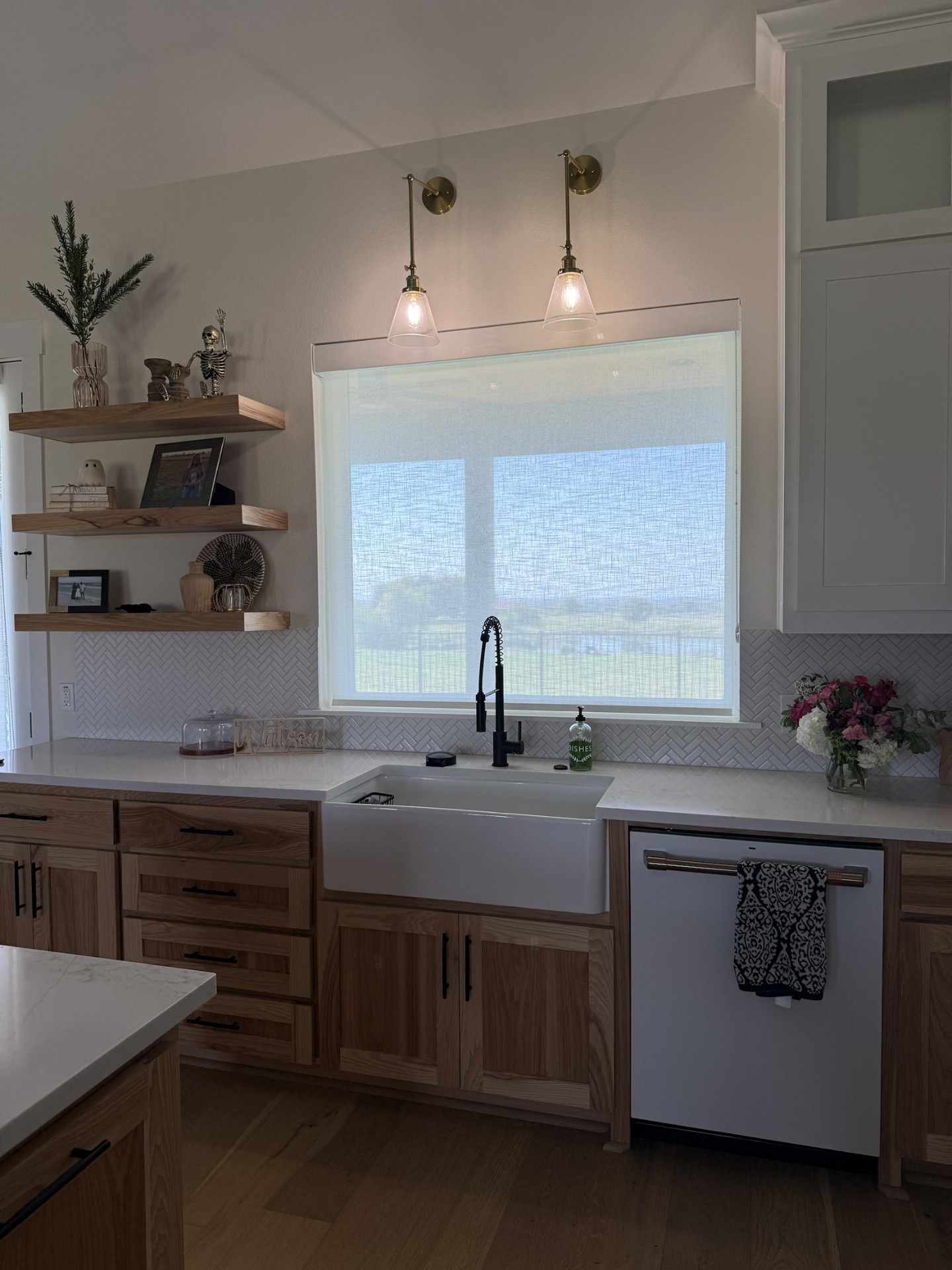 Farmhouse kitchen sink beneath a sunlit window shade